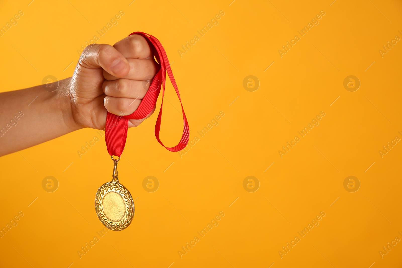 Photo of Woman holding gold medal on yellow background, closeup. Space for text
