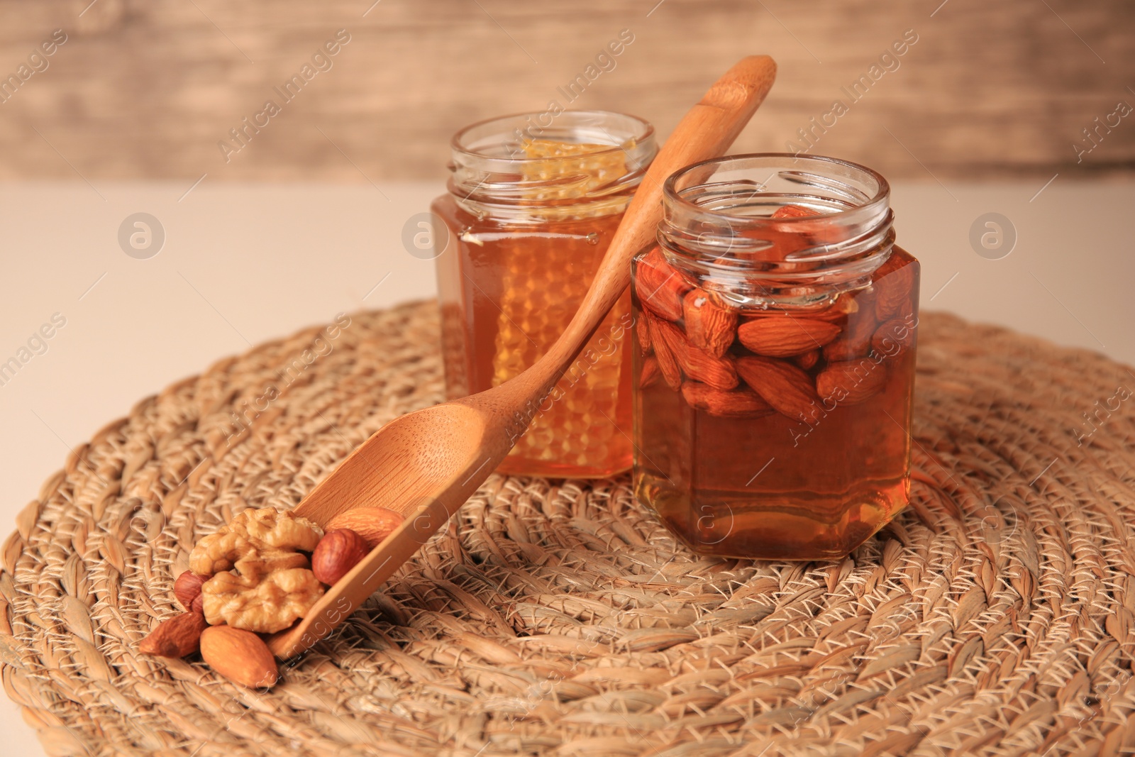 Photo of Jars with honey and different nuts on beige table