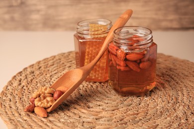 Jars with honey and different nuts on beige table