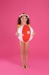 Photo of Cute little child in beachwear with bright inflatable ball on pink background