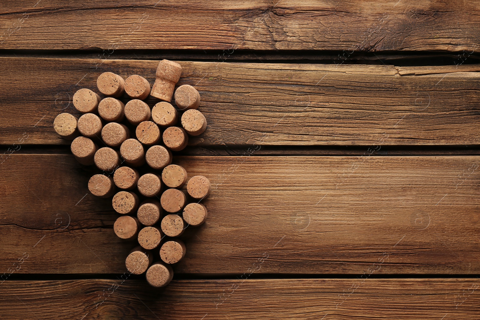 Photo of Grape made of wine bottle corks on wooden table, top view. Space for text