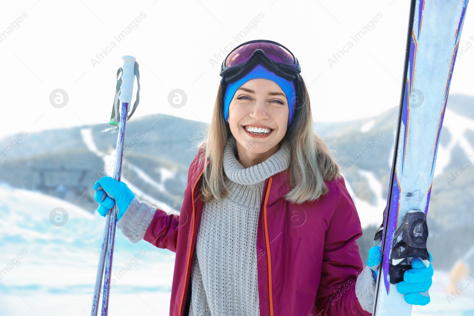 Photo of Happy young woman with ski equipment spending winter vacation in mountains