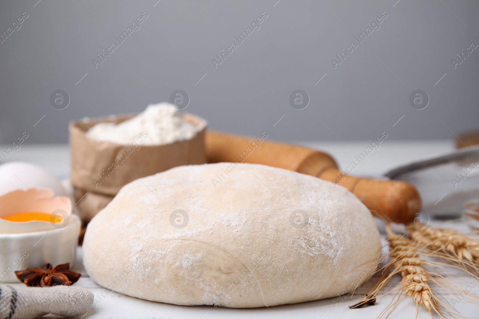 Photo of Fresh dough and ingredients on white wooden table, closeup