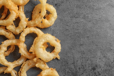 Photo of Delicious golden breaded and deep fried crispy onion rings on gray background, top view. Space for text