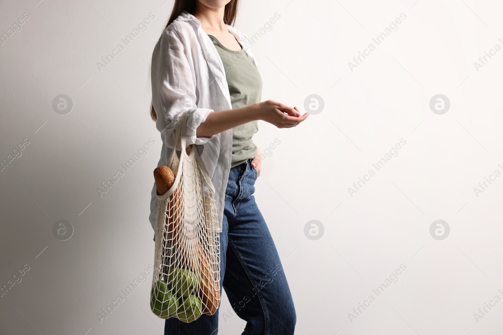 Photo of Woman with eco bag full of products on white background, closeup. Space for text