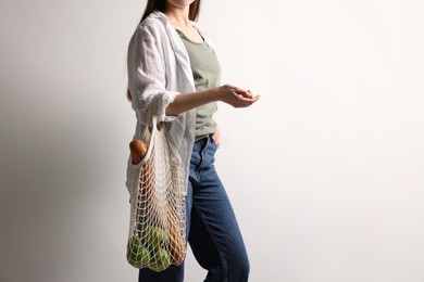 Woman with eco bag full of products on white background, closeup. Space for text