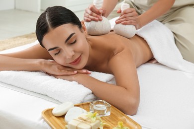 Young woman receiving herbal bag massage in spa salon