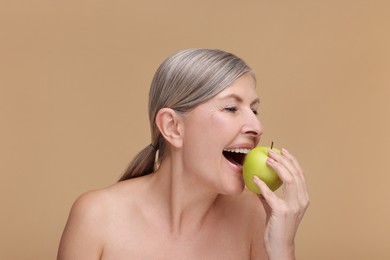 Photo of Beautiful woman eating fresh apple on beige background. Vitamin rich food