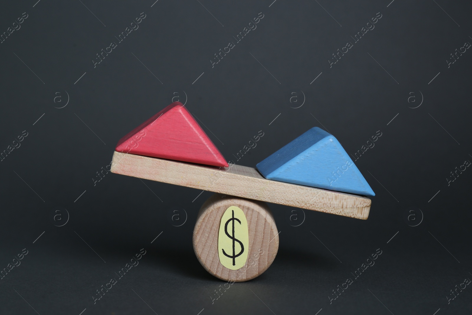 Photo of Gender pay gap. Wooden triangles as male and female symbols on miniature seesaw against black background
