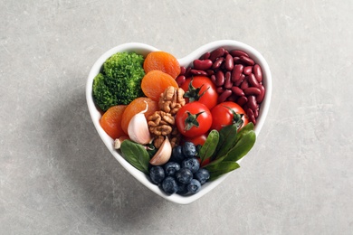 Photo of Bowl with products for heart-healthy diet on grey background, top view