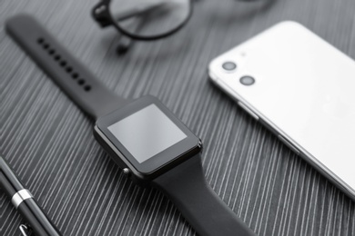 Photo of Stylish smart watch, phone and pen on black table, closeup