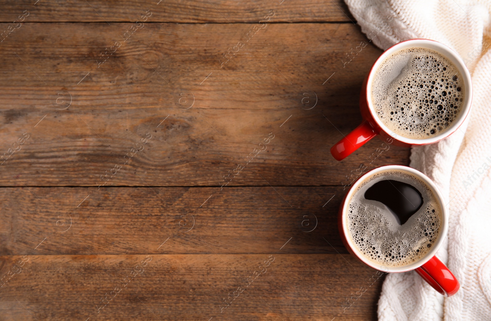 Photo of Flat lay composition cups of hot coffee and knitted sweater on wooden background, space for text. Winter drink