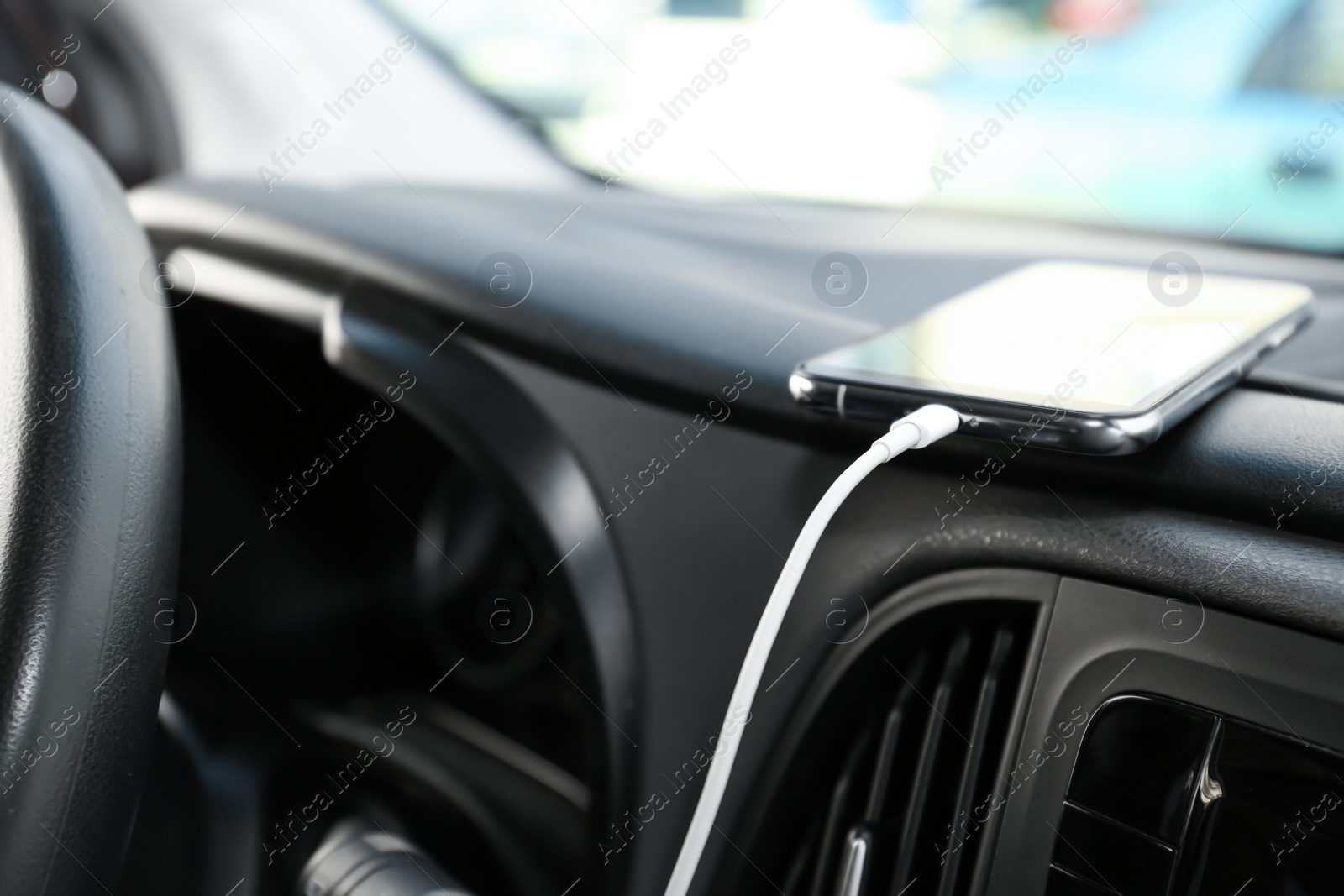 Photo of Smartphone with USB charging cable in modern car