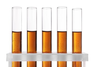 Photo of Test tubes with brown liquid in stand on white background