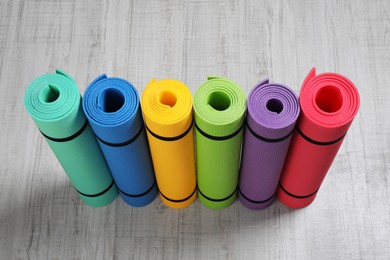 Photo of Bright rolled camping mats on white wooden background