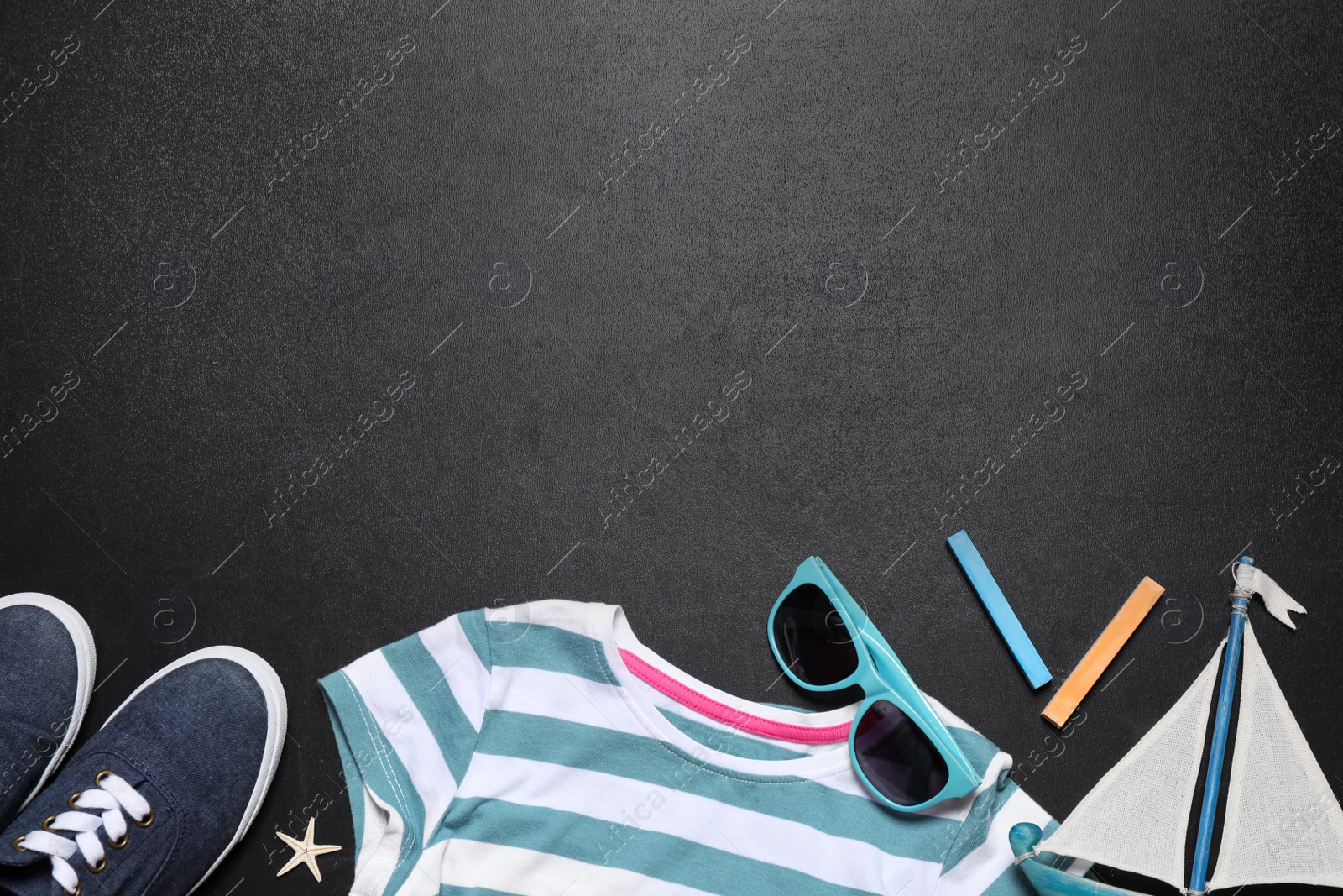 Photo of Flat lay composition with child's clothes on blackboard, space for text. School holidays