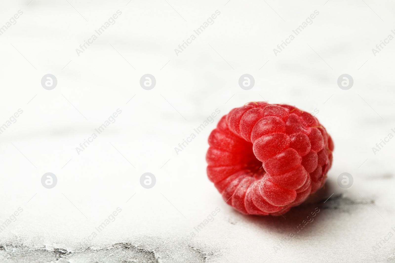 Photo of Delicious ripe raspberry on white marble table, closeup. Space for text