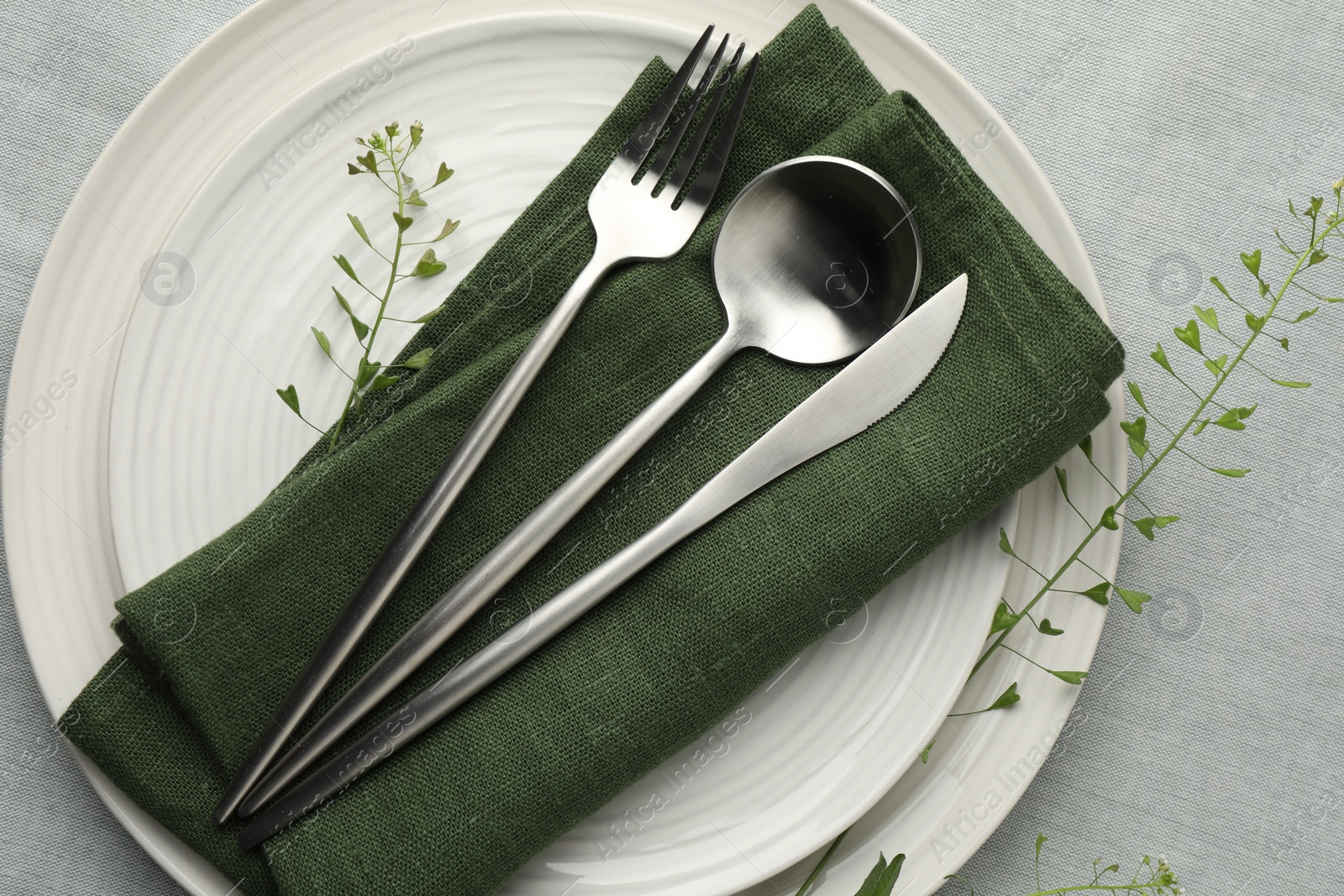 Photo of Stylish setting with cutlery, leaves and plates on grey table, top view