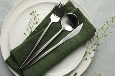 Photo of Stylish setting with cutlery, leaves and plates on grey table, top view