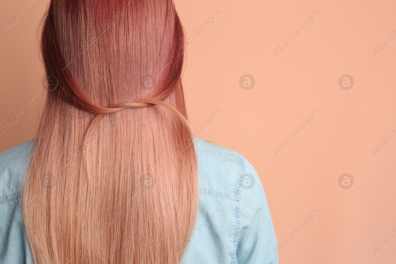 Photo of Woman with bright dyed hair on pale pink background, back view. Space for text