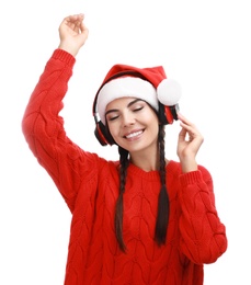 Young woman in Santa hat listening to Christmas music on white background