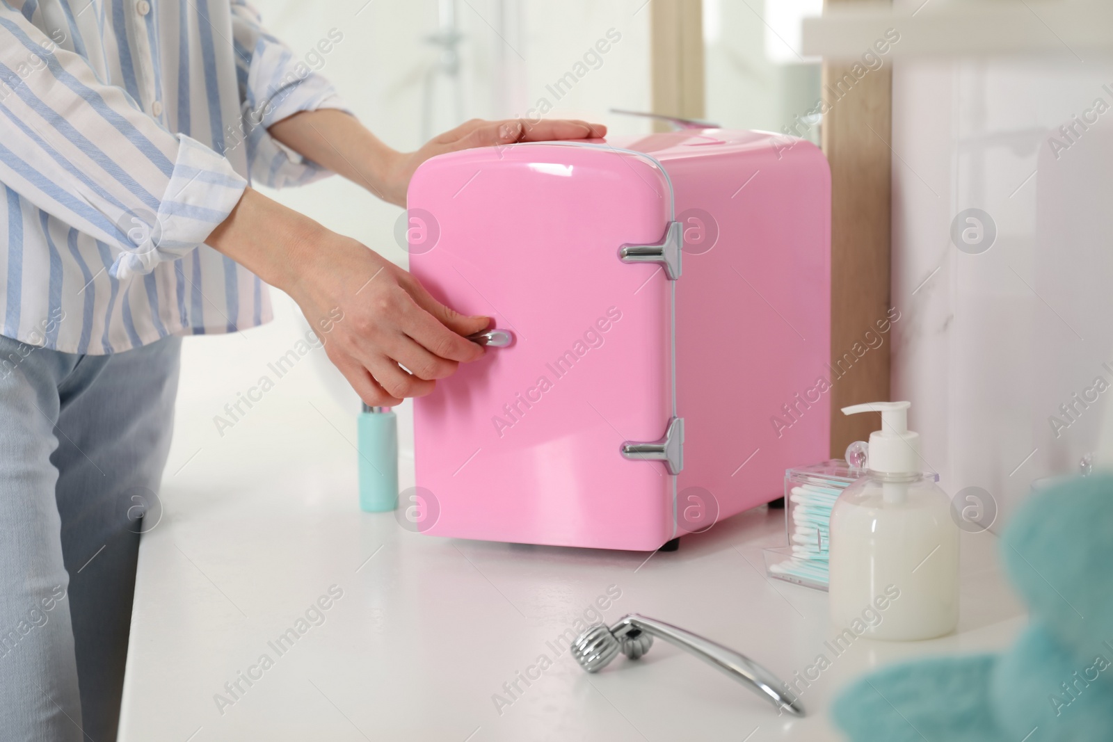 Photo of Woman opening cosmetic refrigerator in bathroom, closeup