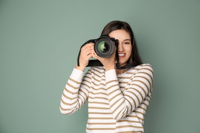 Photo of Young female photographer with camera on grey background