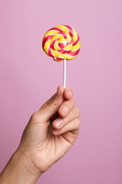 Photo of Woman holding bright tasty lollipop on pink background, closeup