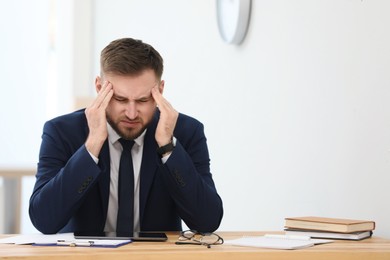 Photo of Man suffering from migraine at workplace in office. Space for text