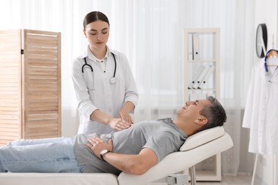 Photo of Gastroenterologist examining patient with stomach pain on couch in clinic