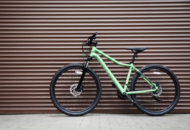 Photo of New modern color bicycle near brown wall outdoors