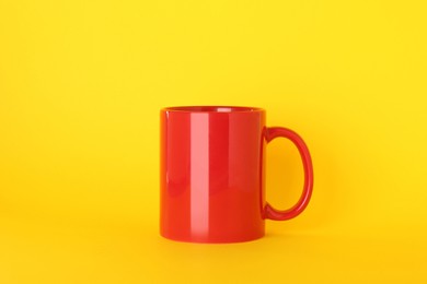 Photo of Blank red ceramic mug on yellow background