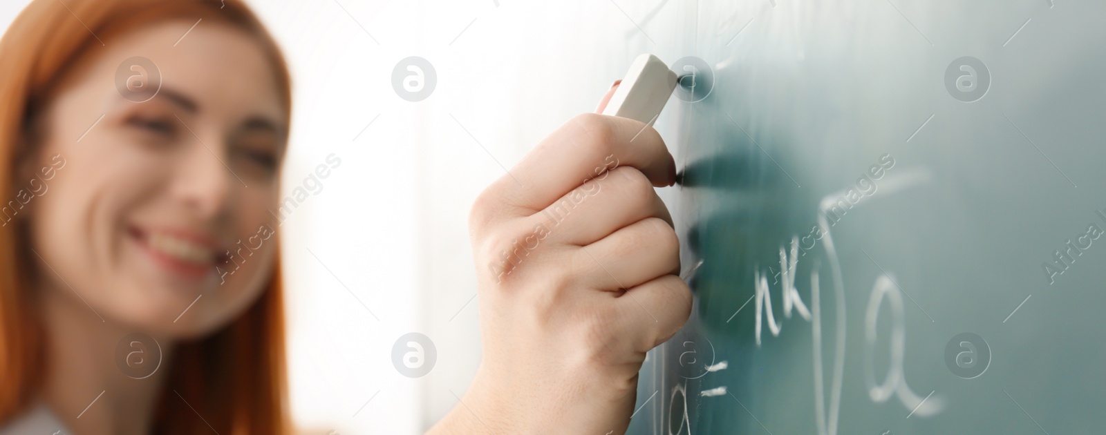 Image of Teacher writing on chalkboard in classroom, closeup. Banner design