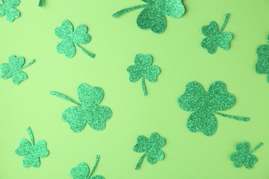 St. Patrick's day. Decorative clover leaves on green background, flat lay