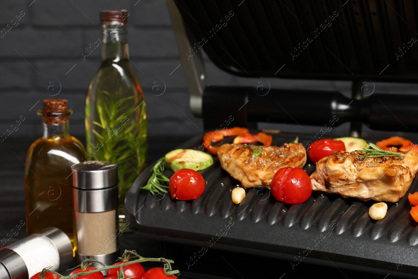 Photo of Electric grill with different products on black table