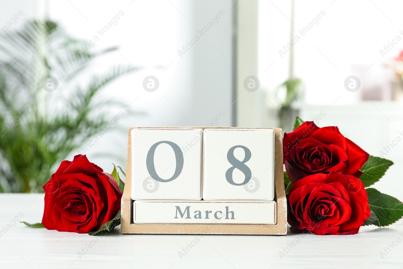 Photo of Wooden block calendar with date 8th of March and roses on table indoors, space for text. International Women's Day