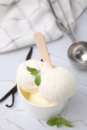 Photo of Delicious ice cream with mint and vanilla pods on white textured table, closeup