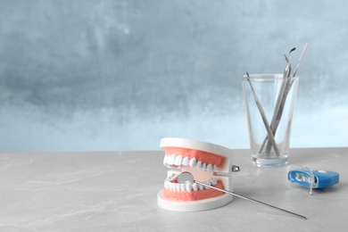 Photo of Typodont teeth, dentist mirror and whitening light lamp on table. Space for text