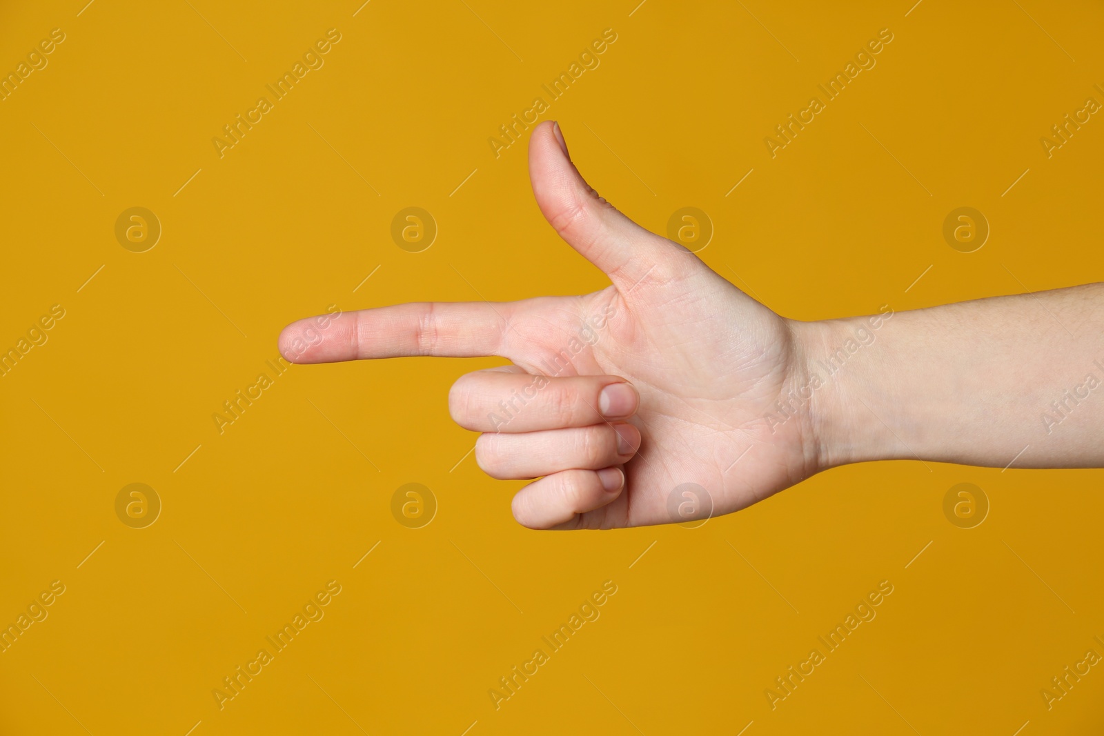 Photo of Woman pointing at something on yellow background, closeup. Finger gesture