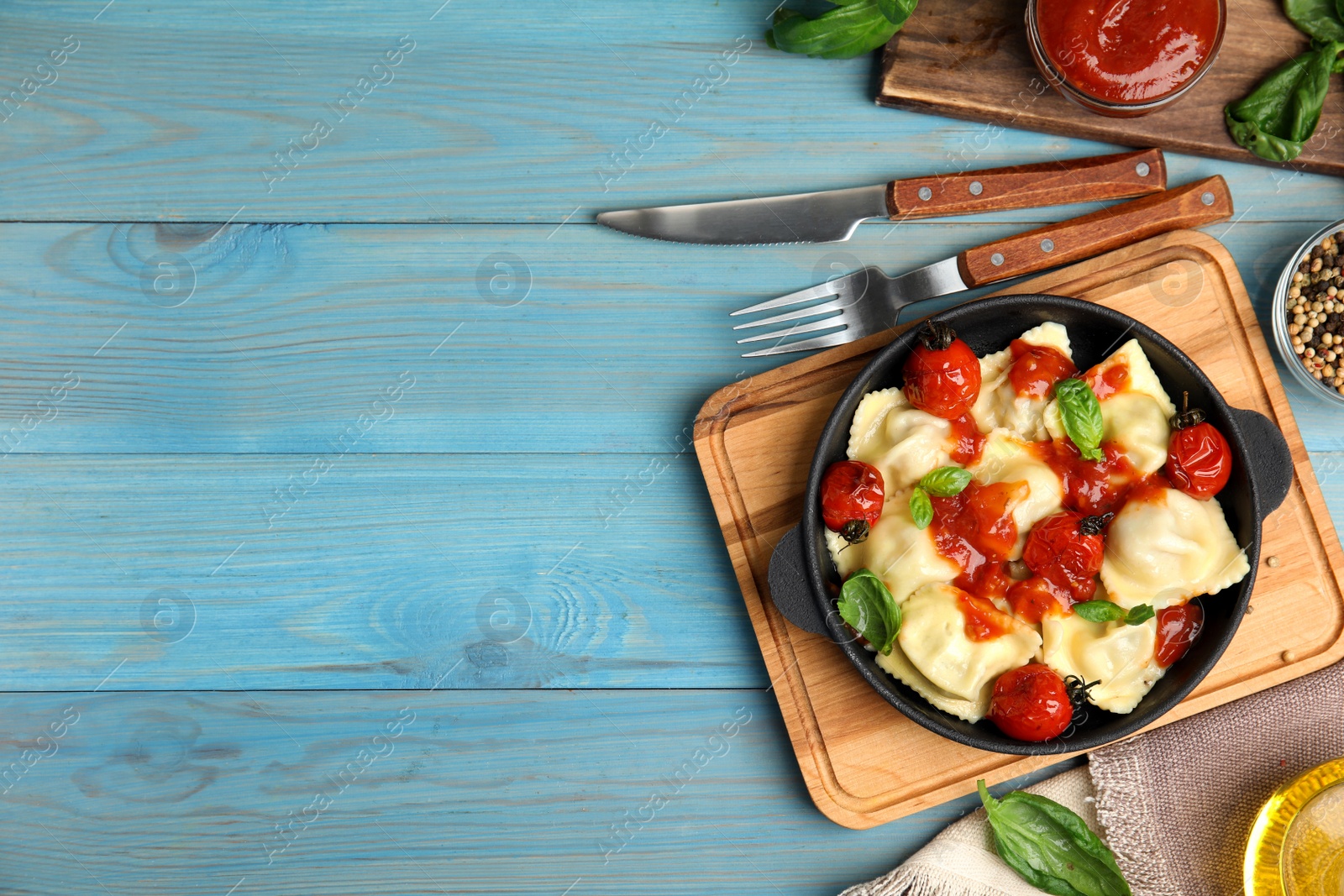 Photo of Tasty ravioli with tomato sauce served on blue wooden table, flat lay. Space for text