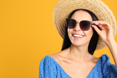 Photo of Beautiful woman wearing sunglasses on yellow background. Space for text