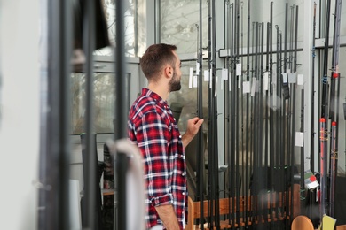 Photo of Man choosing fishing rod in sports shop