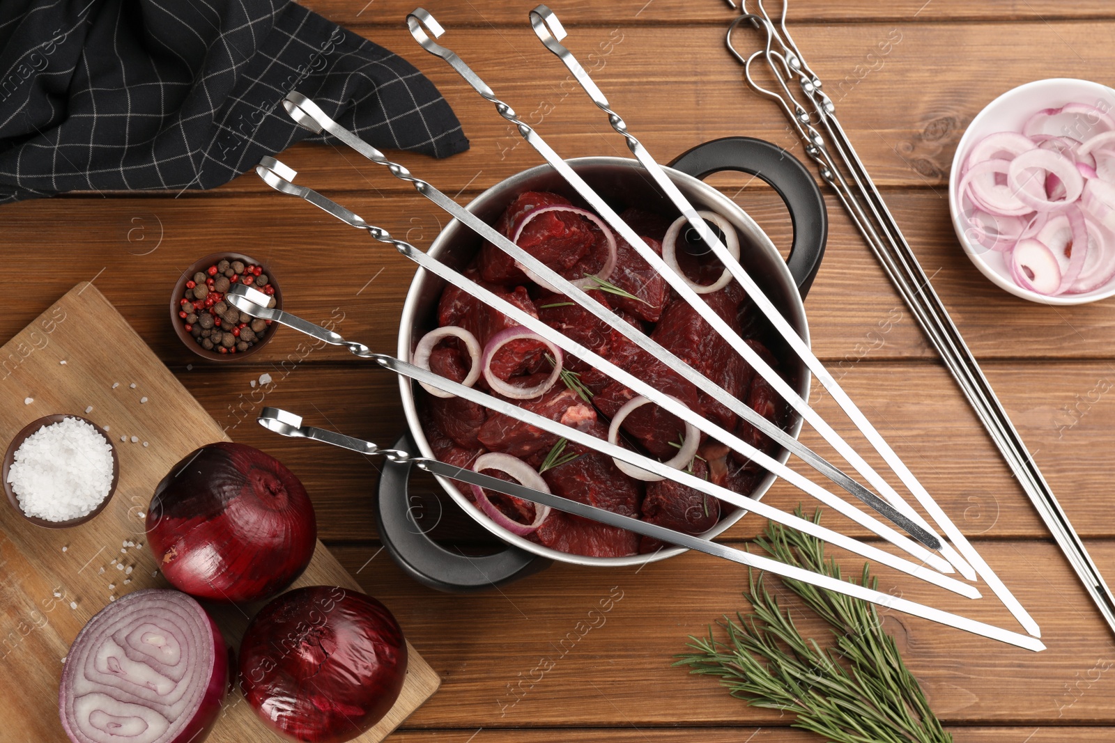 Photo of Flat lay composition with metal skewers and bowl of raw meat on wooden table