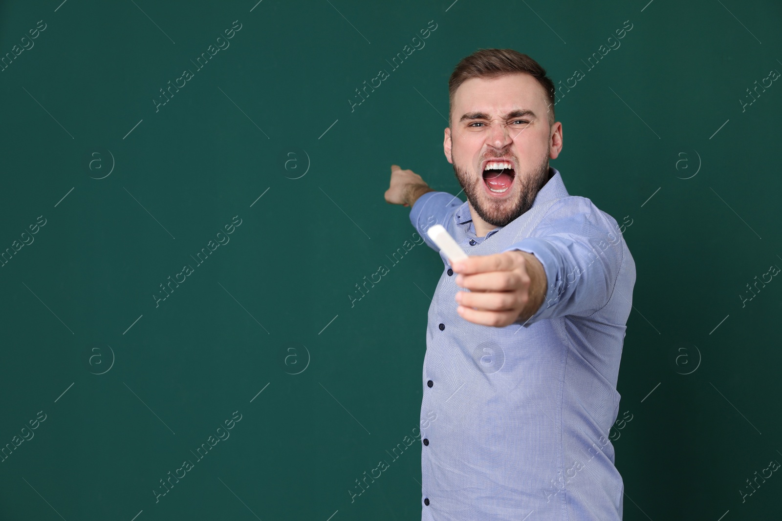 Photo of Portrait of emotional teacher with chalk on green background. Space for text