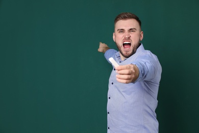 Portrait of emotional teacher with chalk on green background. Space for text