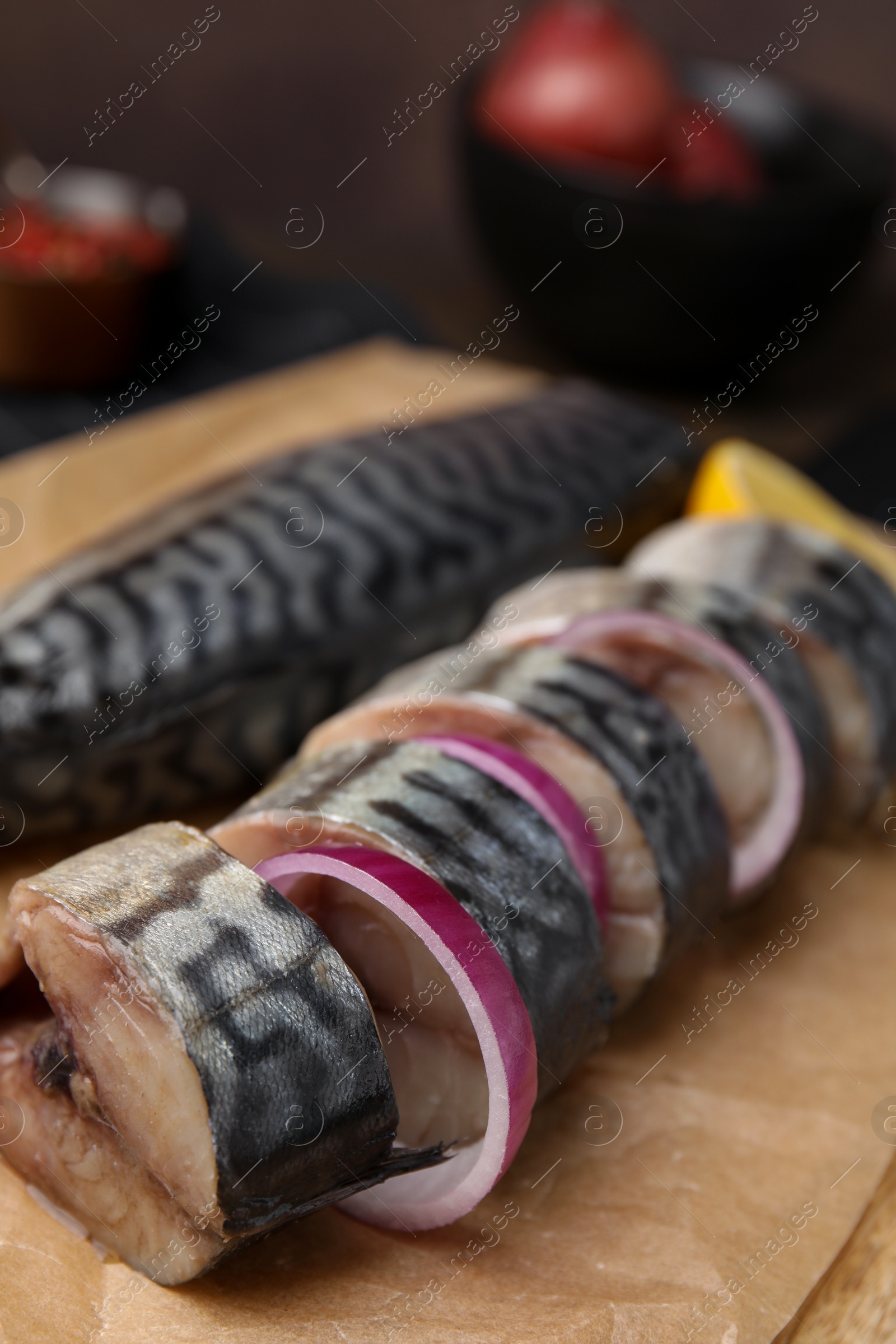 Photo of Tasty salted mackerel, onion and lemon on parchment, closeup