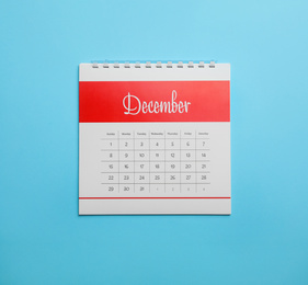 Photo of December calendar on light blue background, top view