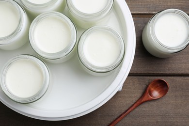 Photo of Modern yogurt maker with full jars on wooden table, flat lay