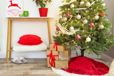 Photo of Beautiful Christmas tree with red skirt indoors