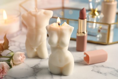 Photo of Beautiful male and female body shaped candles on white marble table